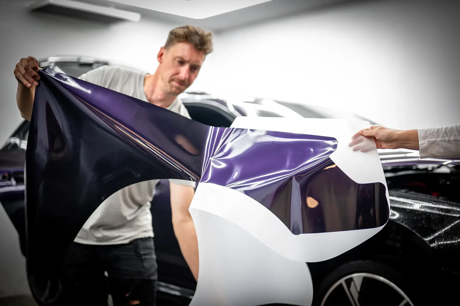 Installers applying purple colour PPF film to a vehicle at the Tiger Tint & Wrap workshop